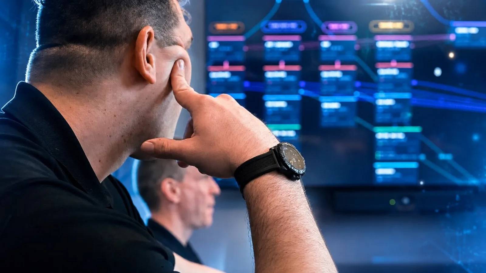Two Aligned Technology Partners engineers studying a network topology map on a large operations display